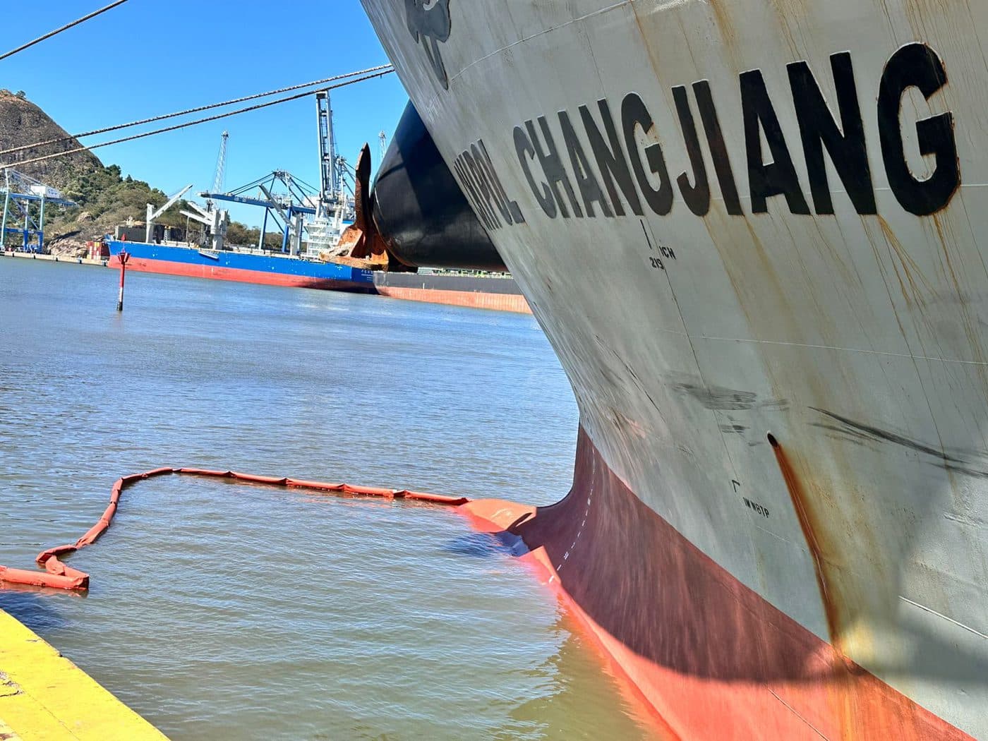 Operação de contenção ambiental ao redor de navio no porto