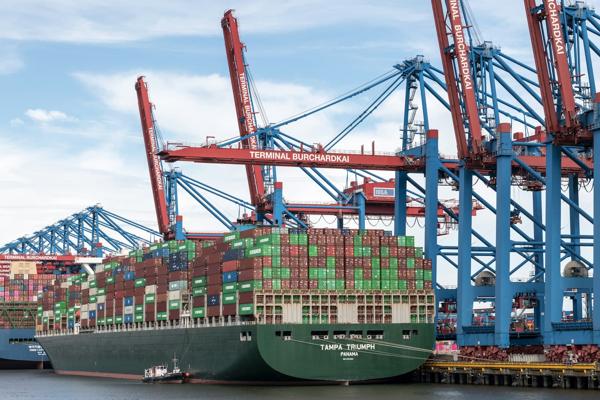 Navio porta-contêineres atracado sob guindastes do terminal portuário